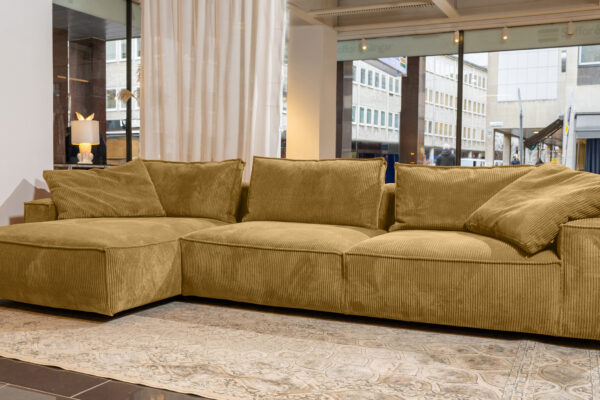 robust-djup-divansoffa-i-gult-manchestertyg-framför-en-vit-gardin